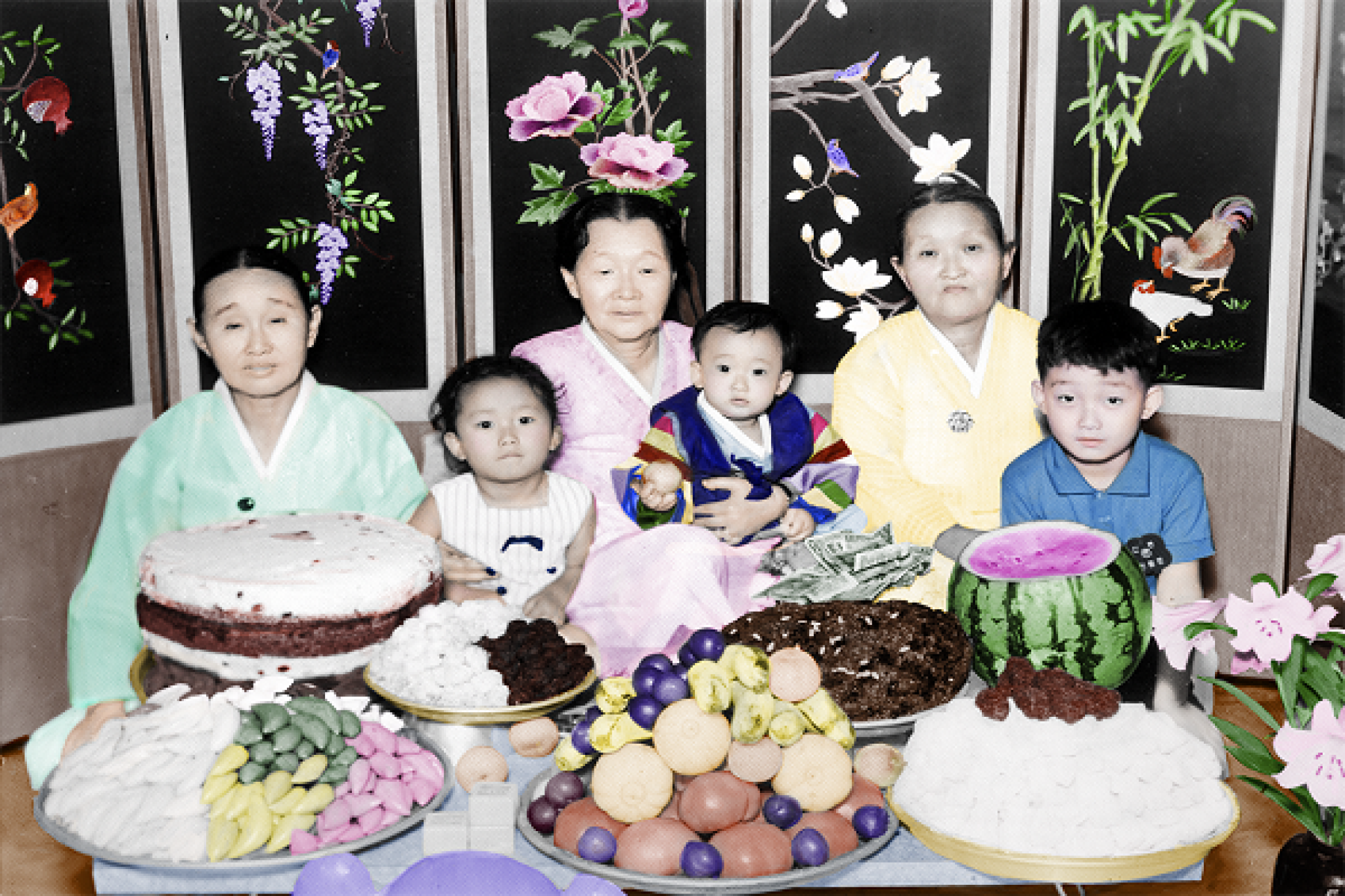 A hand-coloured photograph of a family celebrating ‘doljanchi’, from Lee Grant's series of found images titled “Lost and Found: Chromatic Dialogues”